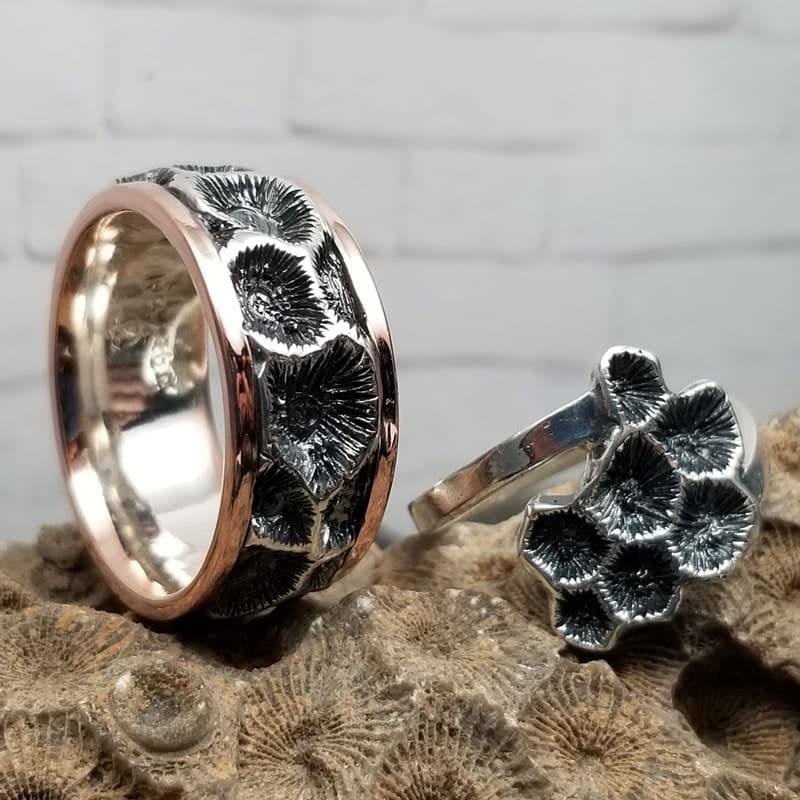 Wide band with an oxidized, honeycomb-like fossil-coral texture between rose-toned rails, beside a matching textured ring