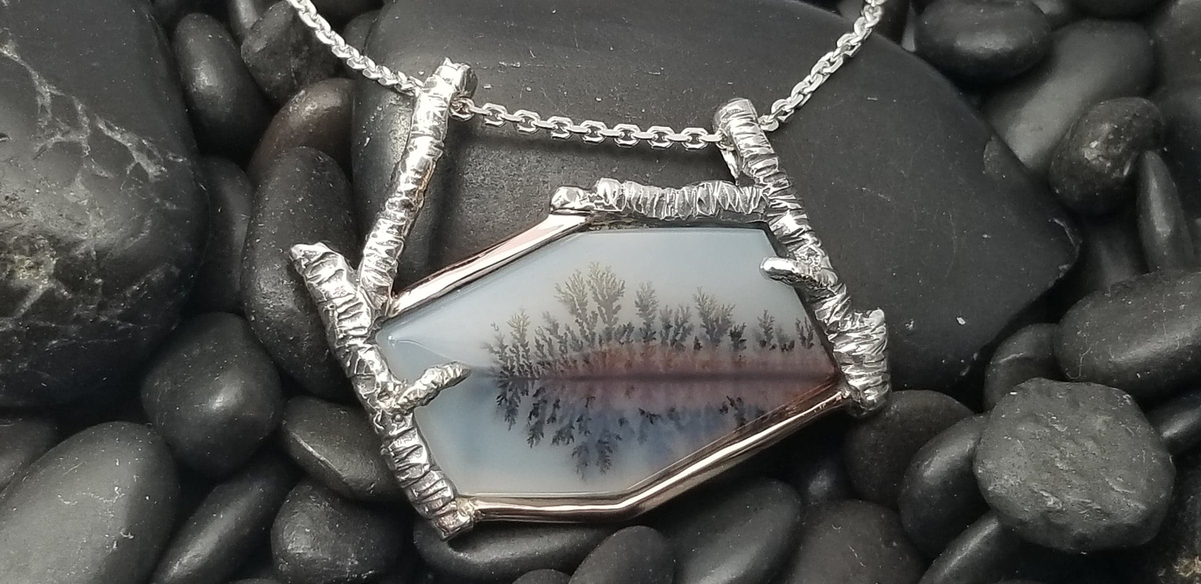 Whispers of the Birch: a pendant framing a stone with a natural landscape pattern between sculpted birch-branch forms