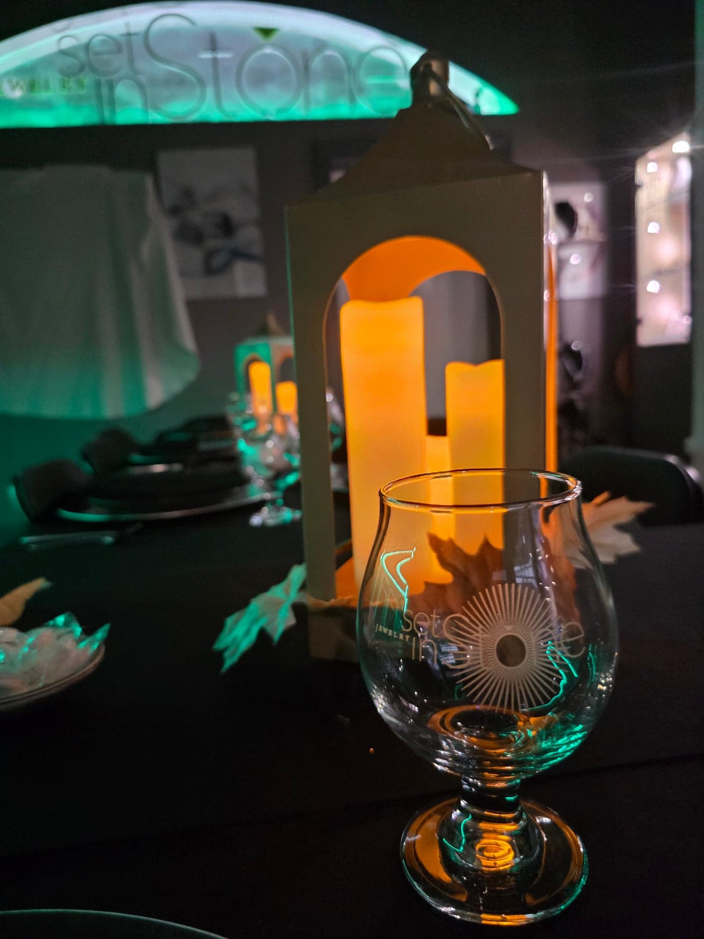 A Jewelry Set in Stone glass glowing by candlelight in front of a lantern, the studio sign lit green behind it