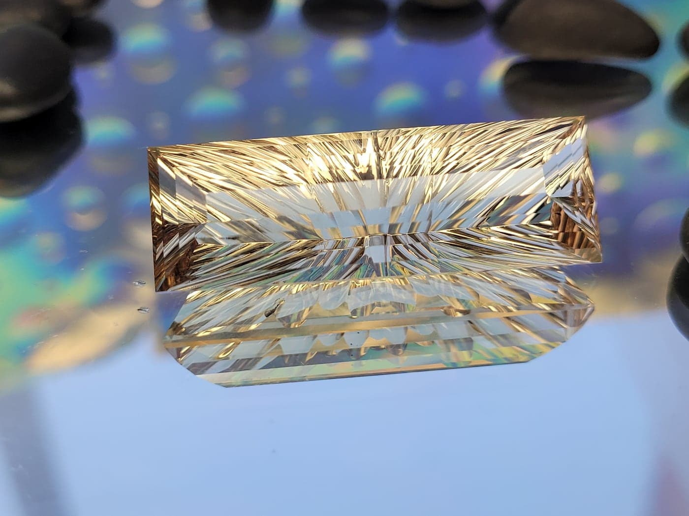 A long golden gemstone carved with sweeping grooves that catch the light like sunrays