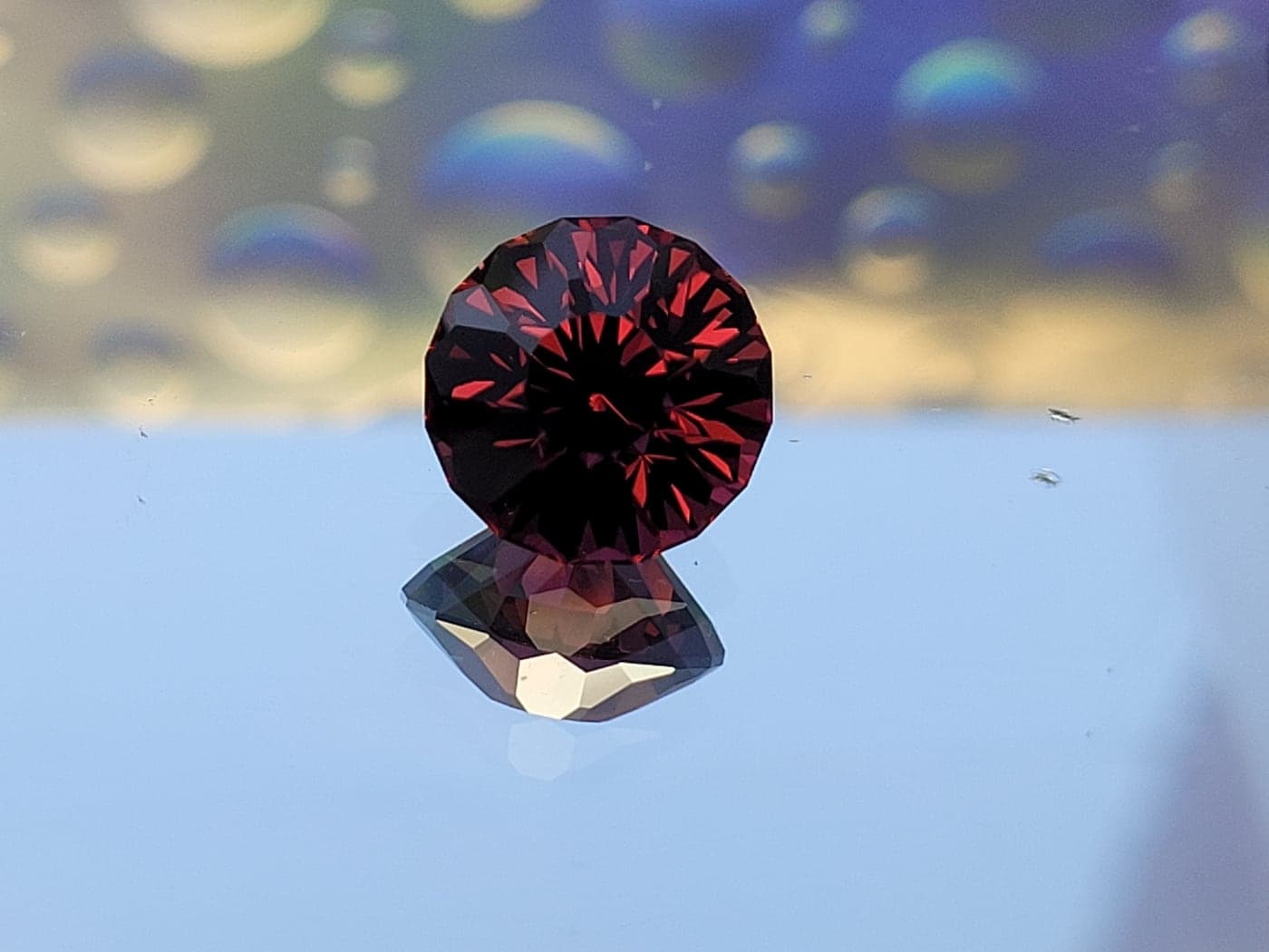 A deep red round gemstone flashing bright red facets