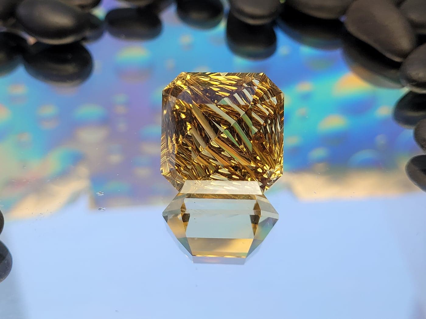 A golden square gemstone carved with diagonal grooves that glow amber